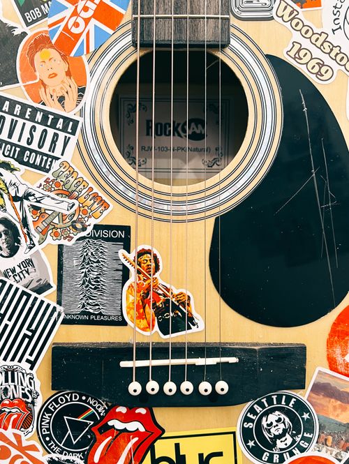 Close up of an acoustic guitar covered in musical stickers