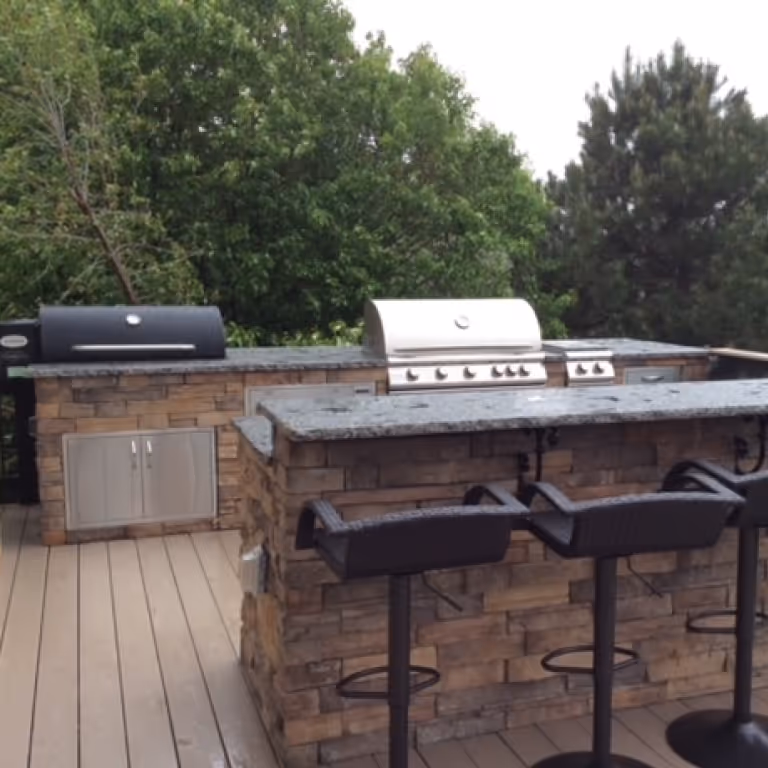 Beautiful outdoor kitchen design with Faux Stone, bar seating and smoker incorporated