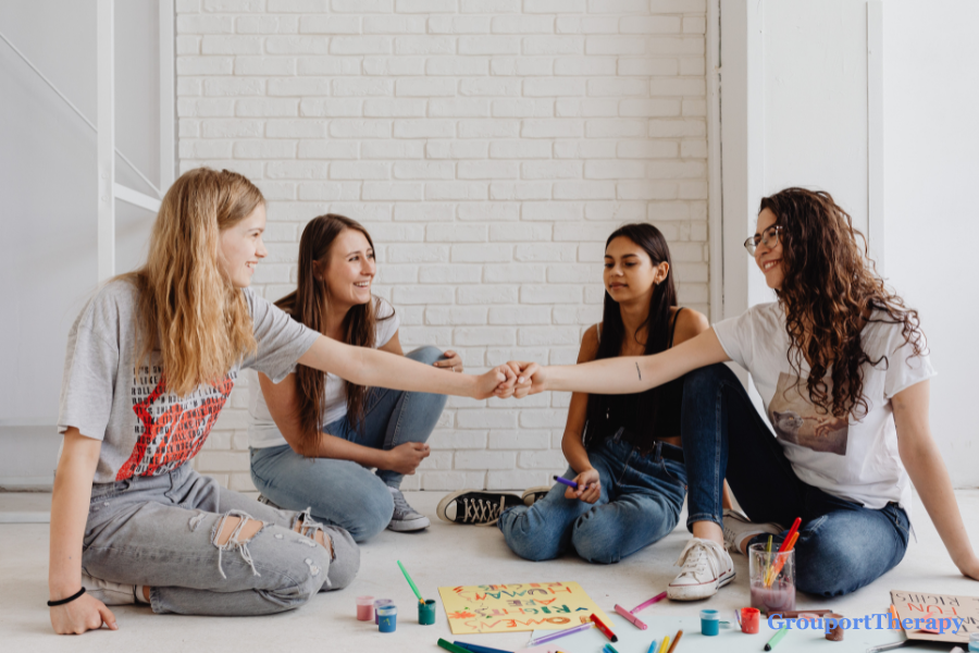 Teen girls sitting together during an art activity, representing friendship, peer support, and emotional connection in therapy