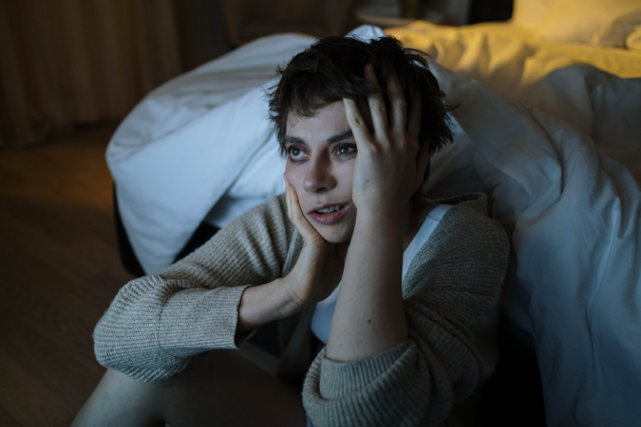 Image 1: Person sitting beside a bed during emotional overwhelm, representing age regression and BPD-related distress