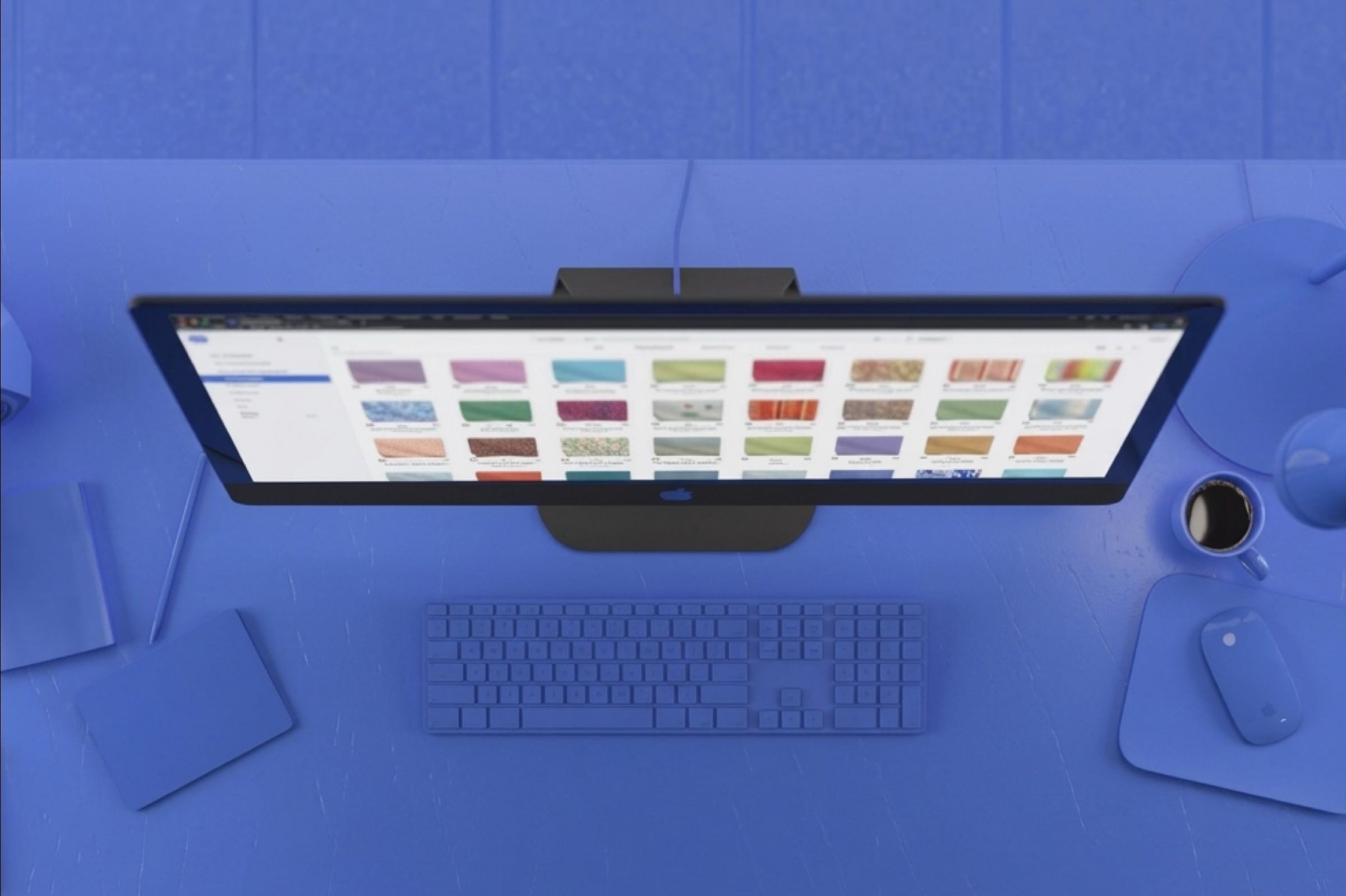 swatchbook's material library on a desktop monitor, seen from above on a blue desk.