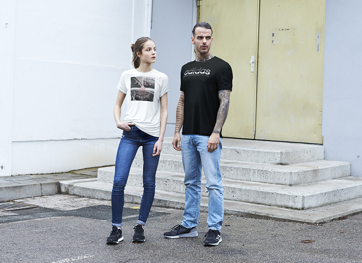 Two rendered models in Adidas T-shirts standing in front of a building doorway.