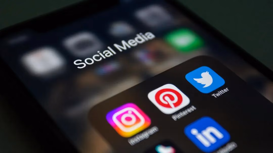 Smartphone in der Hand, auf dem Startbildschirm liegen die Symbole der Social-Media-Apps nebeneinander.