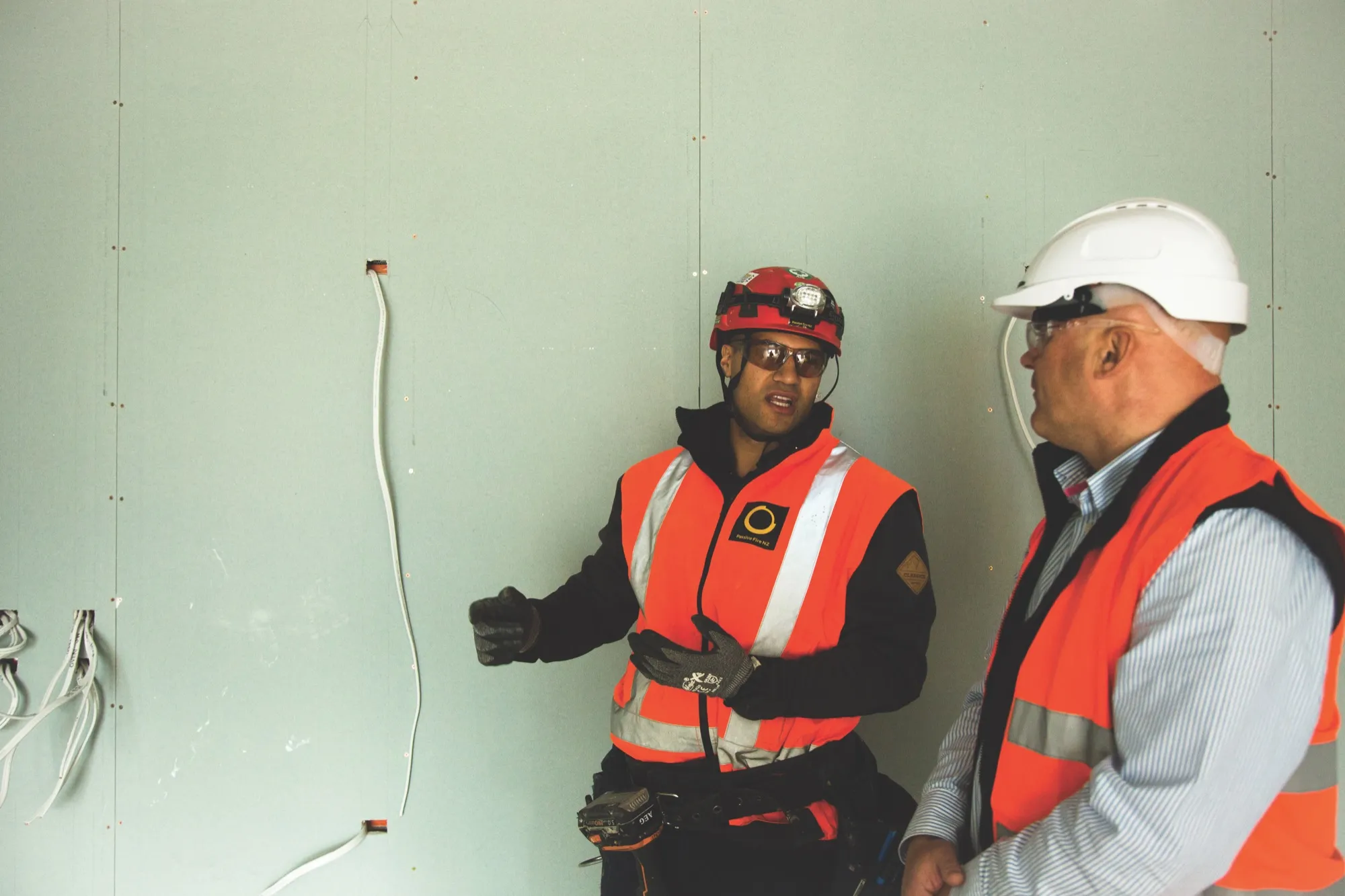 A coach and apprentice discussing electrical wiring on site