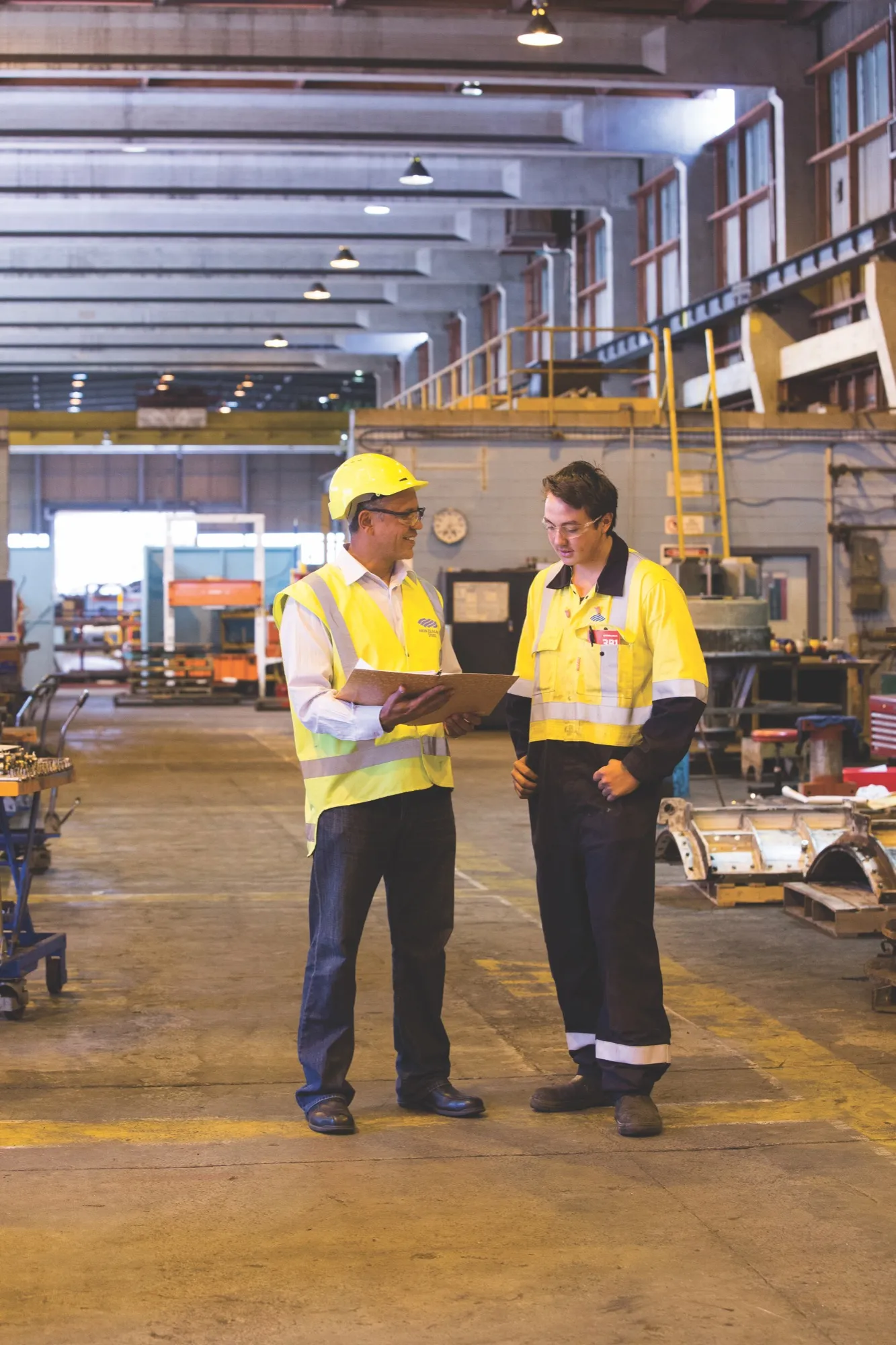 Two workers reviewing a job on a clipboard in a steel plant