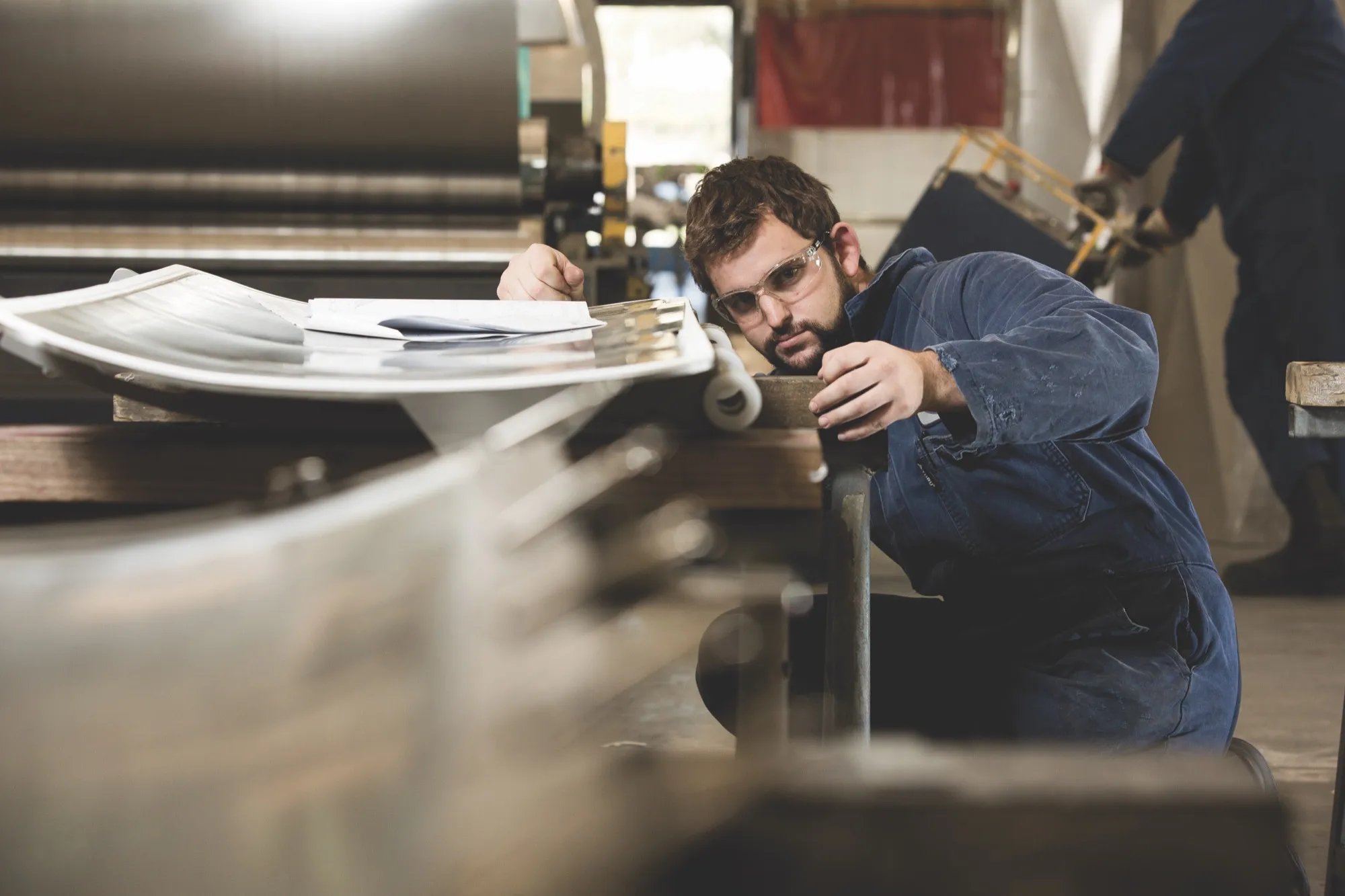A coach and apprentice inspecting an industrial machine