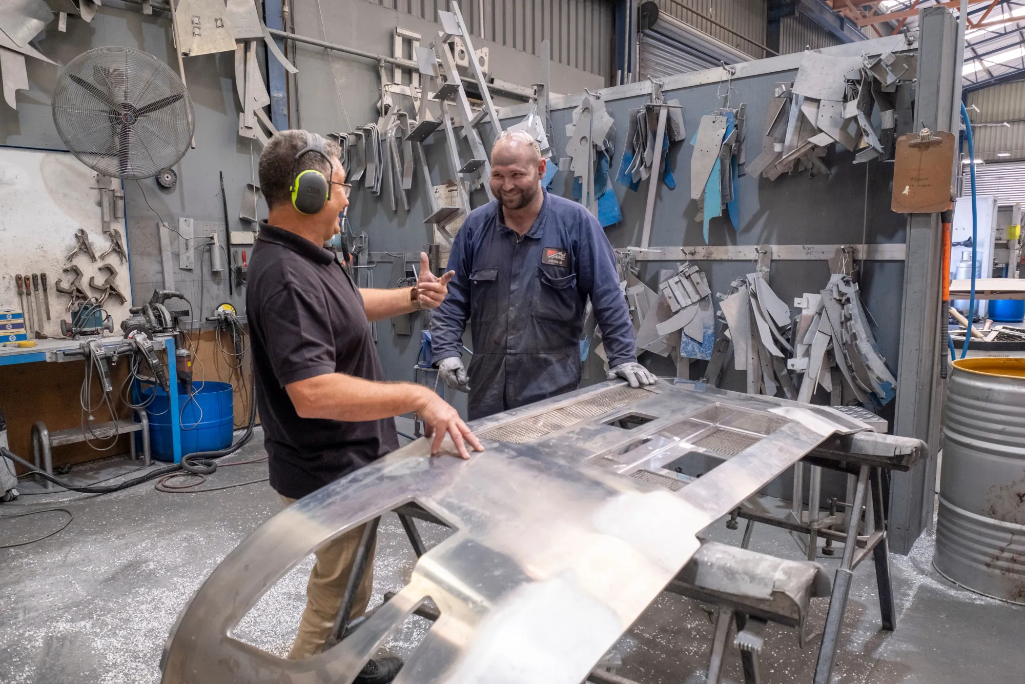 A coach and apprentice inspecting a large metal component