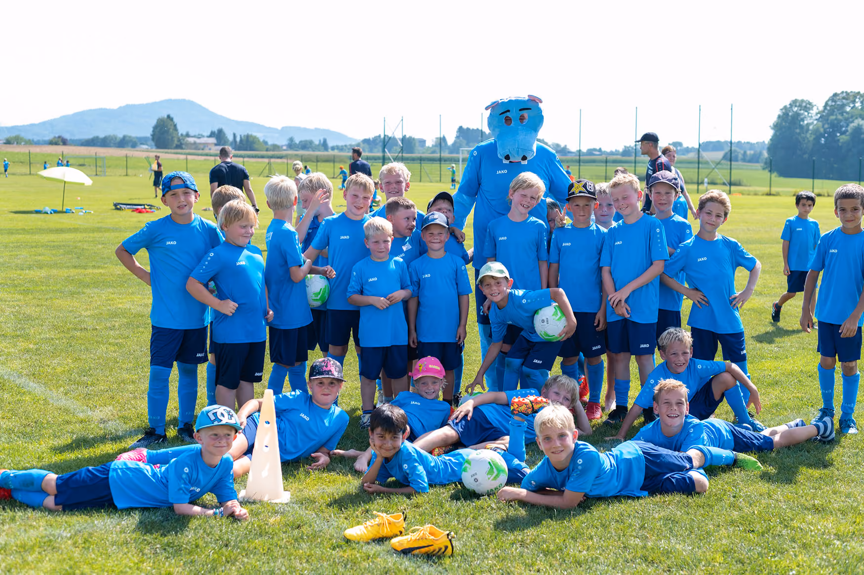 Kinder mit blauem Fußballtrikot spielen Fußball