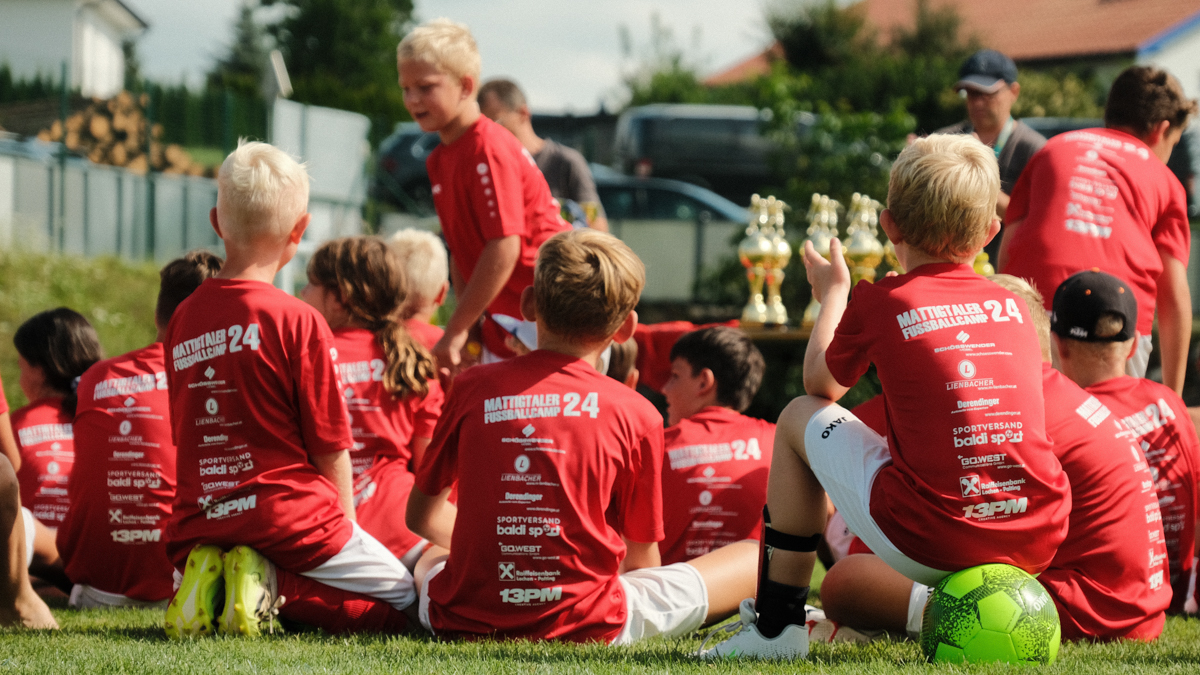 Kinder mit blauem Fußballtrikot spielen Fußball