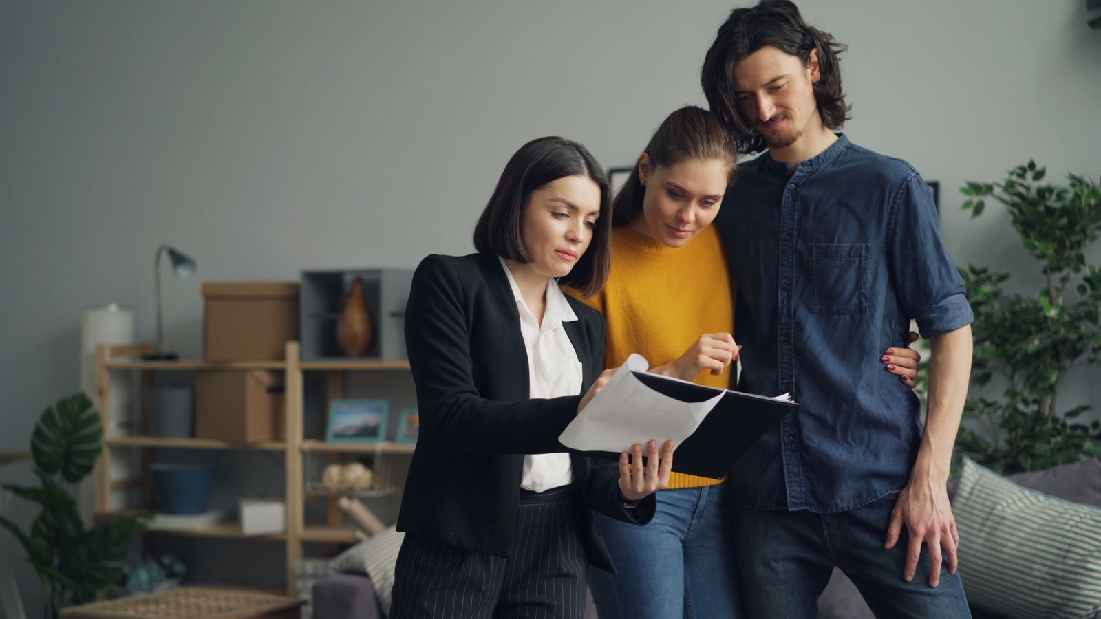 Couple échangeant avec une professionnelle de l’immobilier dans un logement occupé