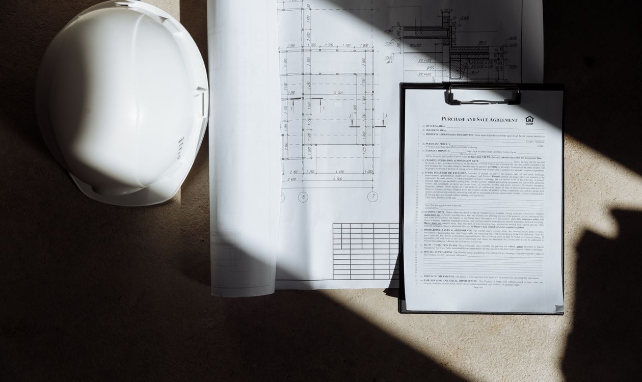 Plans de logement, casque de chantier et dossier de diagnostics avant un compromis