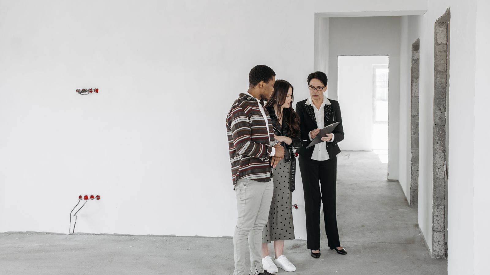 Couple échangeant avec une professionnelle au sujet de documents dans un logement à inspecter