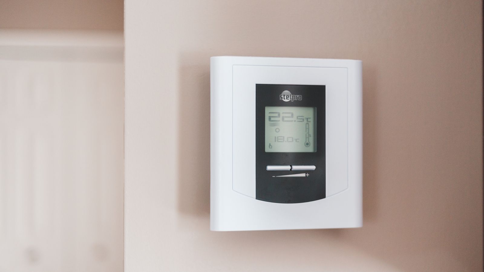 Main réglant un thermostat mural programmable dans un logement