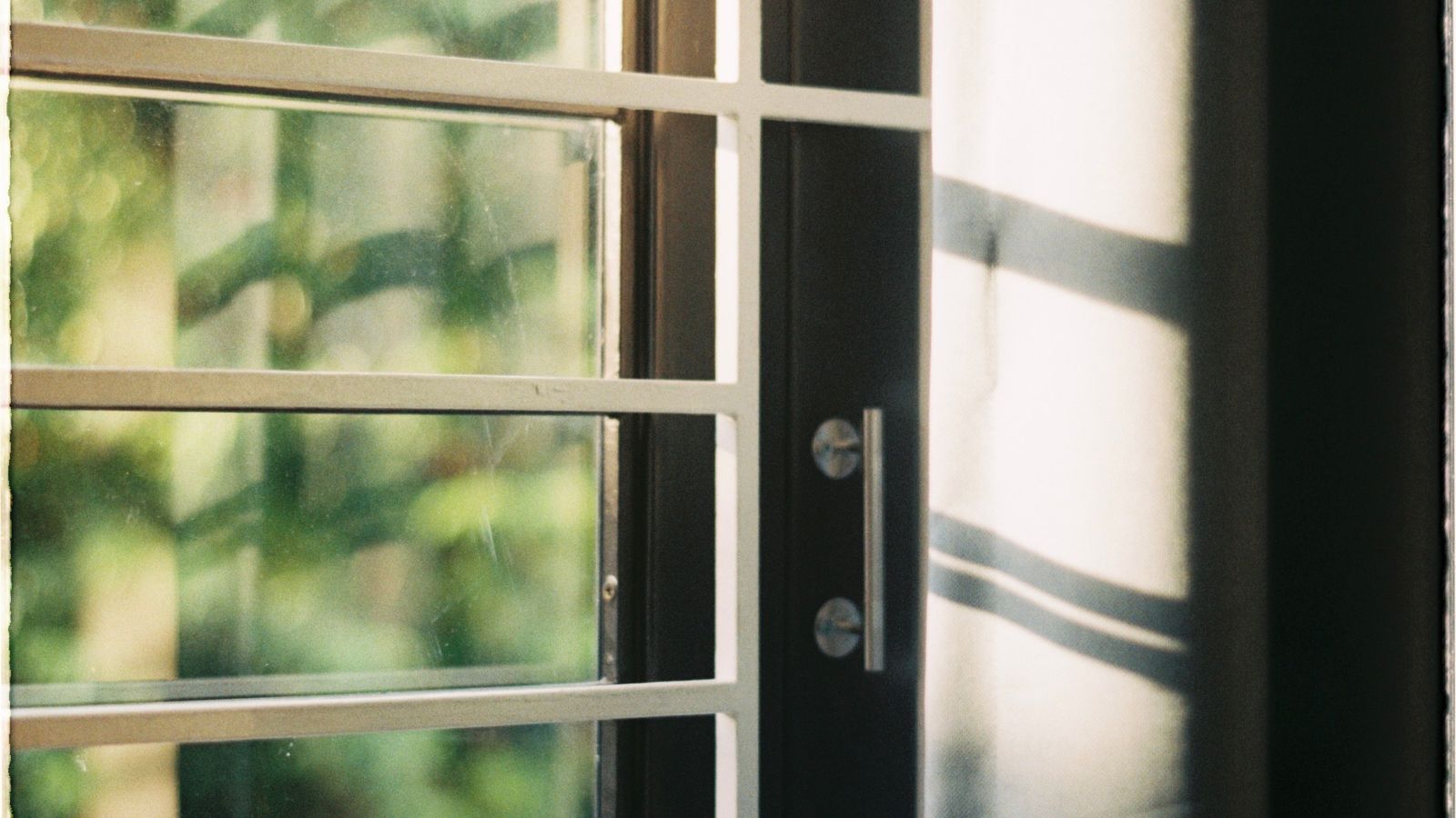 Rayons du soleil filtrés par des volets devant une fenêtre de logement