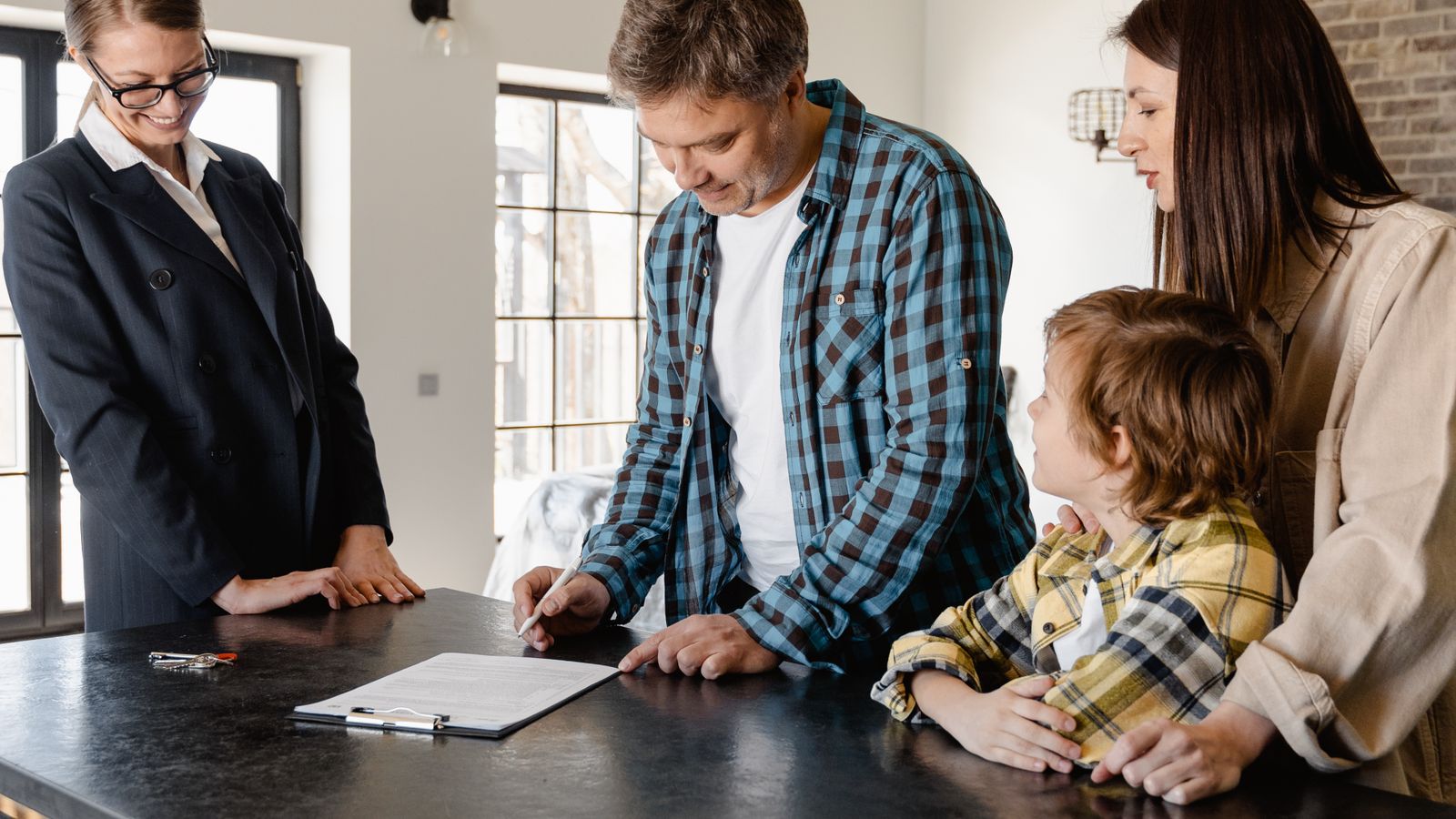Famille examinant des documents immobiliers avec une professionnelle dans une maison