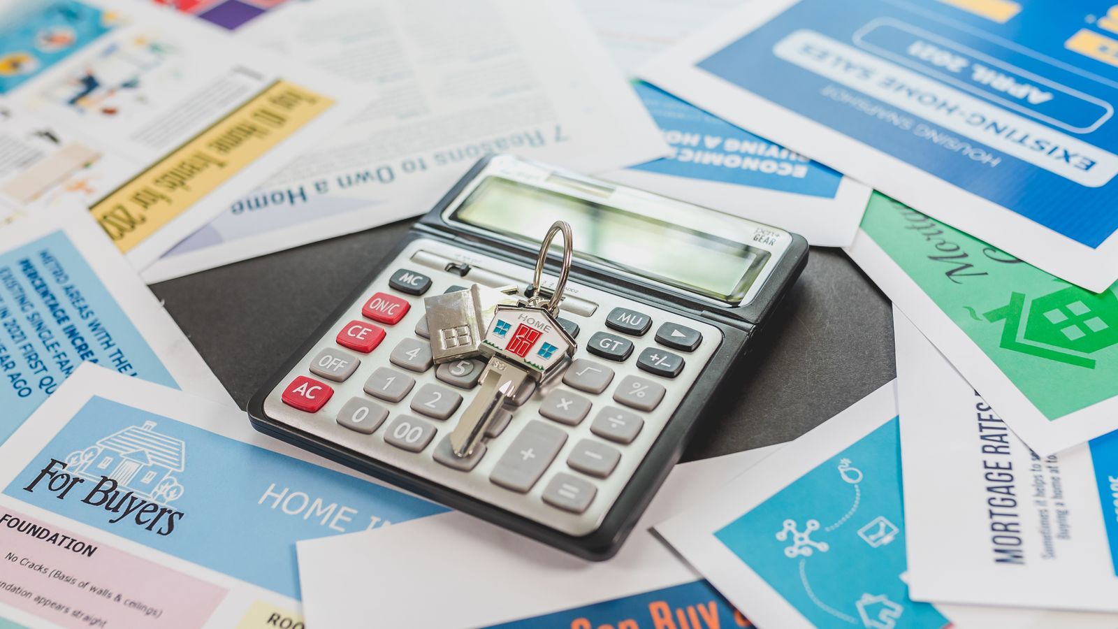 Calculatrice posée sur des documents de financement et des annonces immobilières