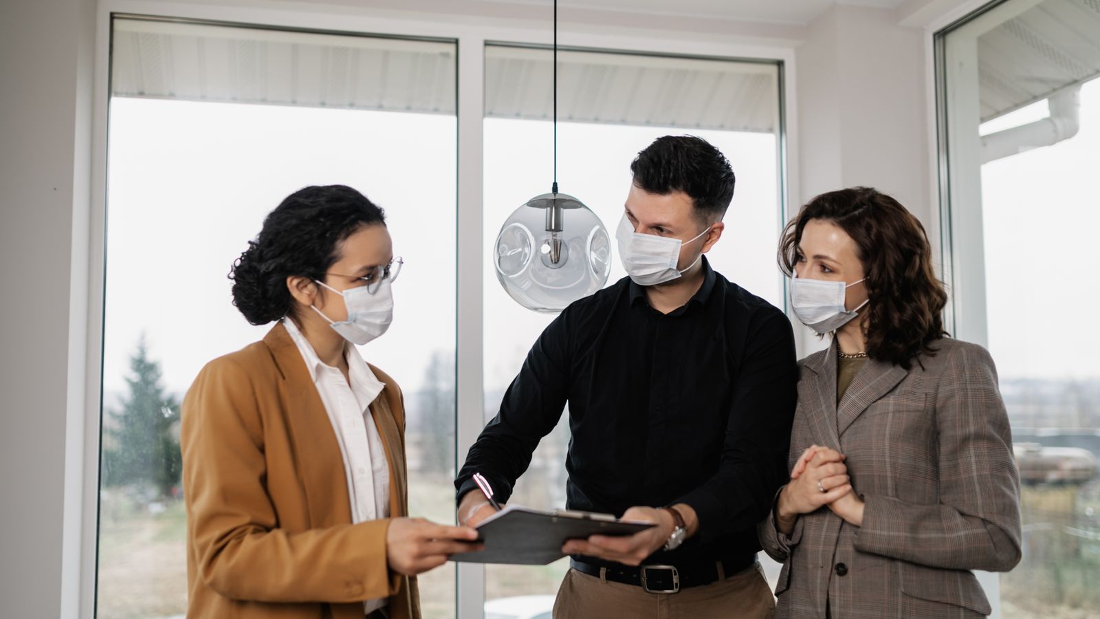 Couple examinant un contrat immobilier avec une professionnelle autour d’une table