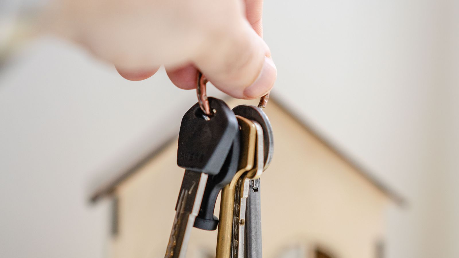 Main tenant des clés devant une petite maison en bois lors d’un projet financé
