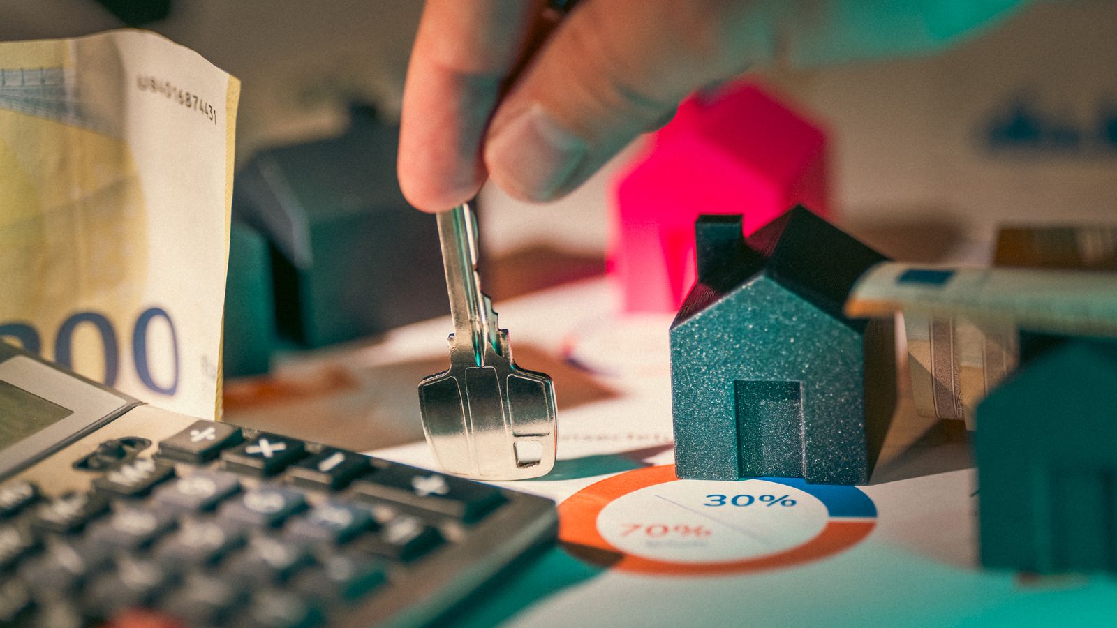 Clés, maison miniature, euros et calculatrice pour établir un budget immobilier