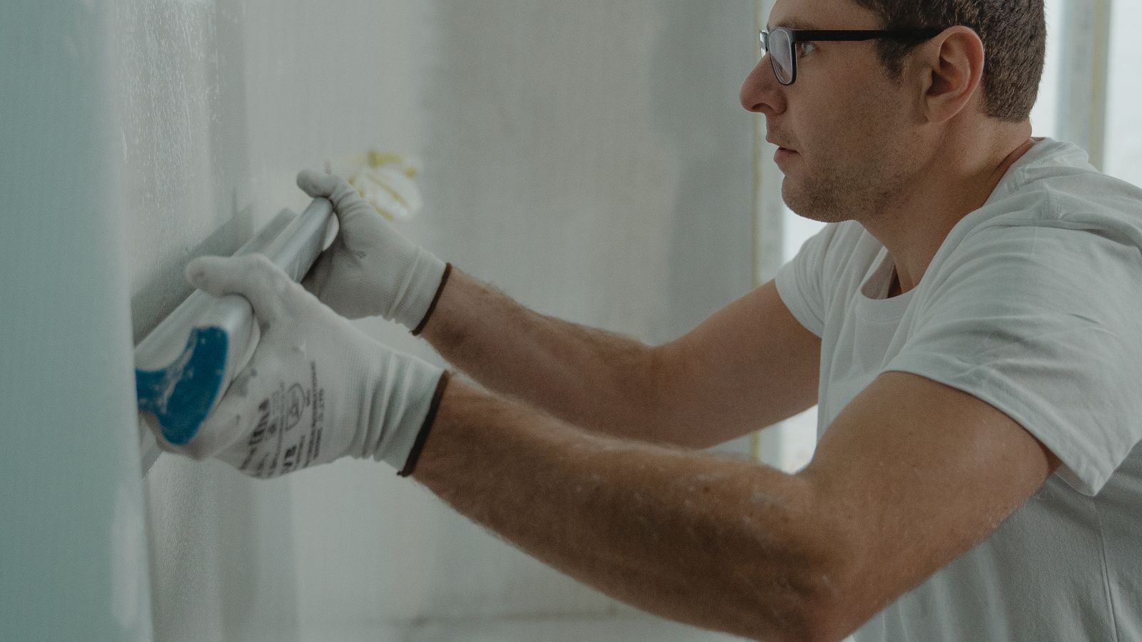 Artisan réparant et repeignant un mur intérieur abîmé