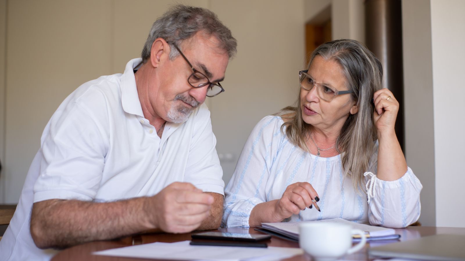 Couple de seniors examinant ensemble des documents patrimoniaux à domicile