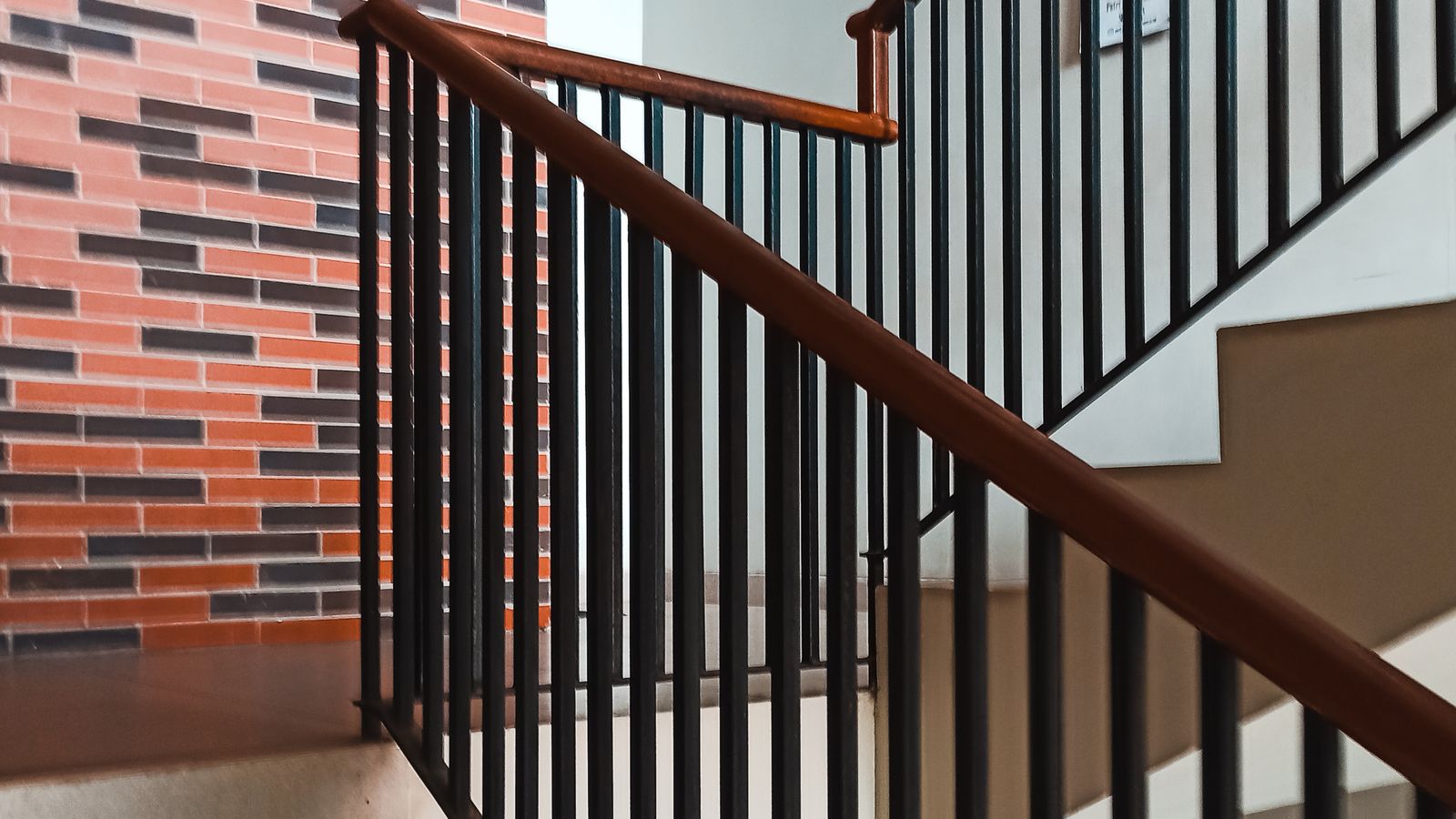 Cage d’escalier moderne avec mur en briques et rampe métallique