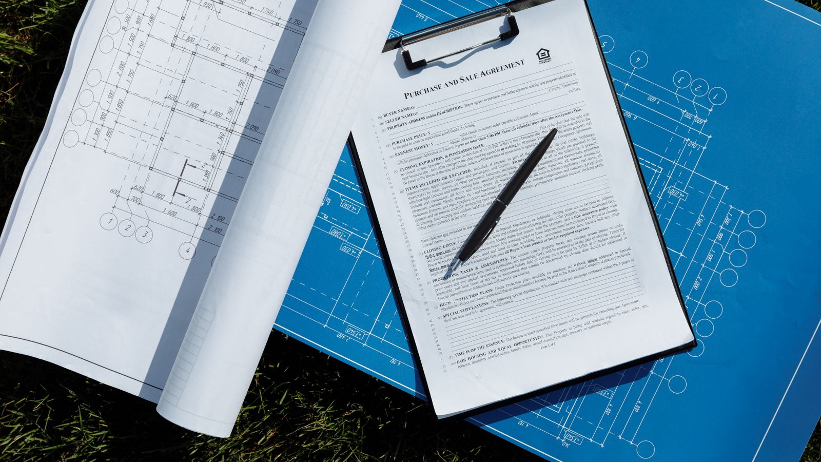 Plans de maison, contrat et stylo disposés sur une table de travail