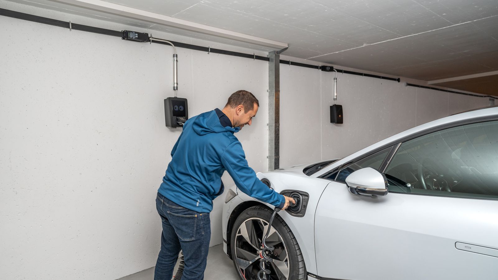 Conducteur branchant une voiture électrique à une borne dans un garage