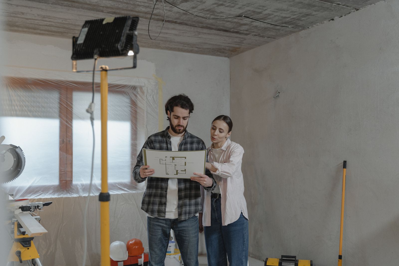 Couple étudiant des plans de rénovation dans un logement en travaux