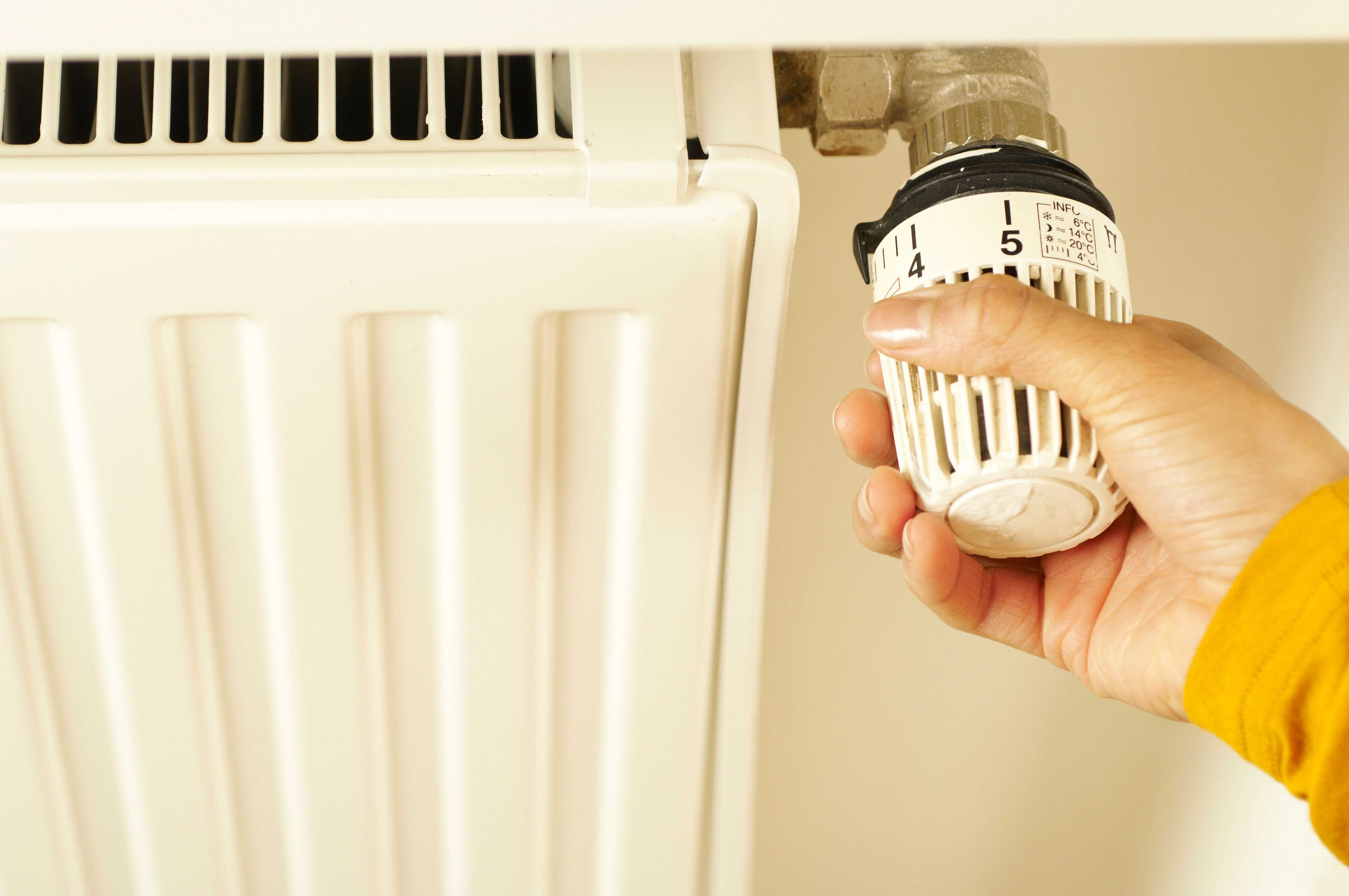 Main réglant la vanne thermostatique d’un radiateur de logement