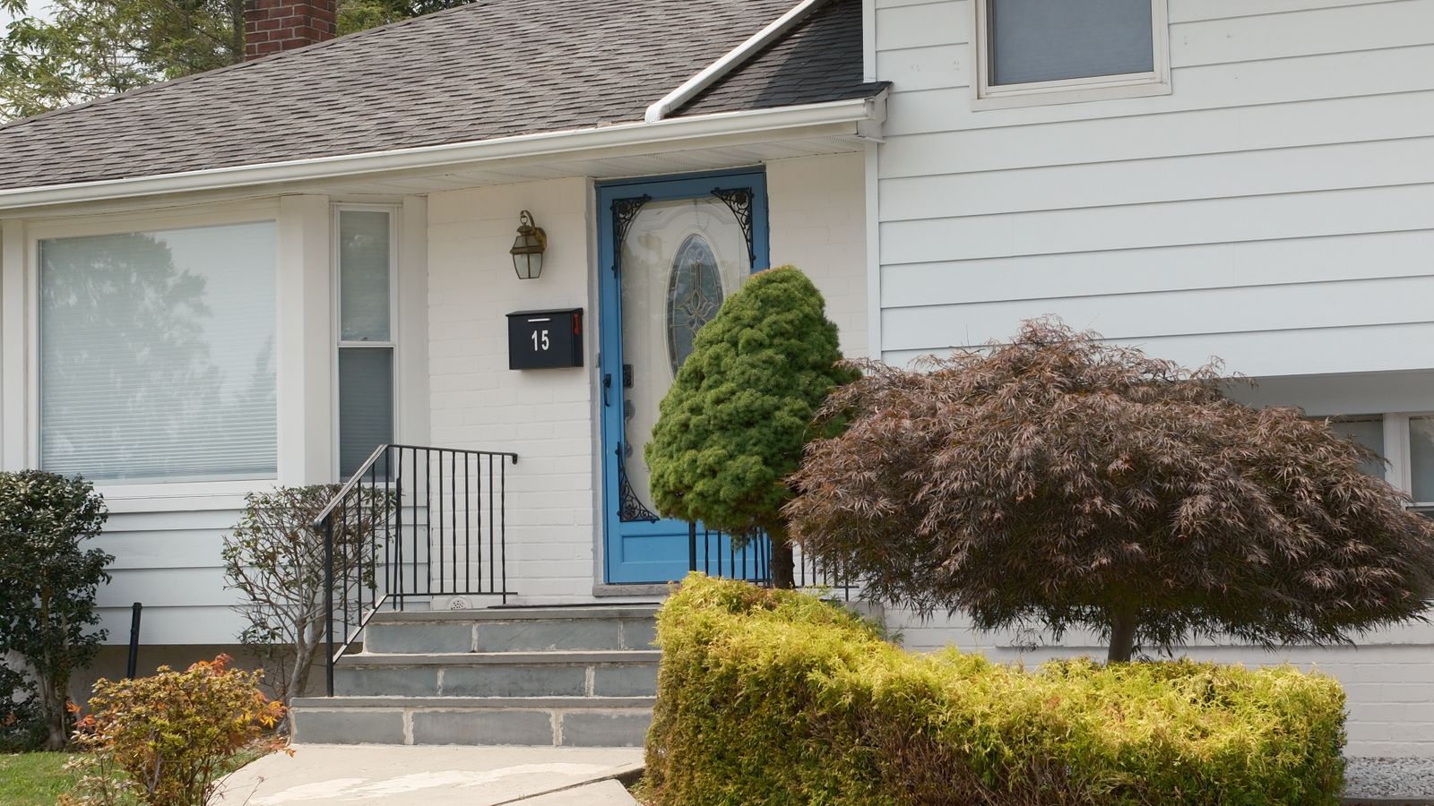 Porte d’entrée bleue d’une maison avec façade et végétation