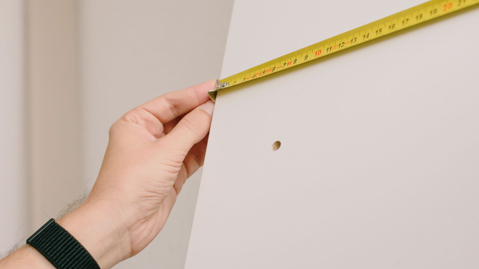 Mesure d’un mur intérieur avec un mètre ruban pendant une rénovation
