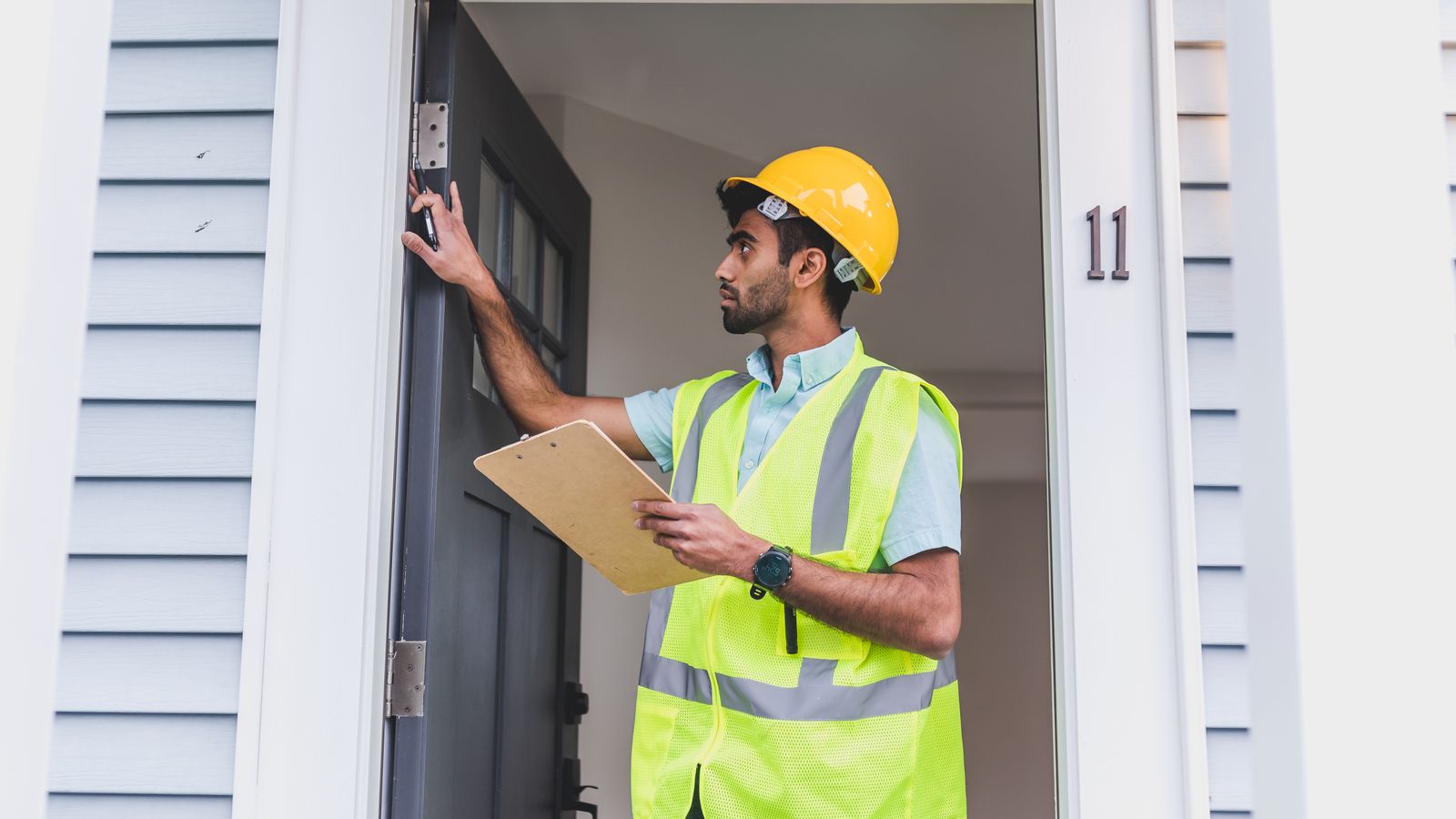 Inspecteur examinant l’entrée d’une maison avec une checklist