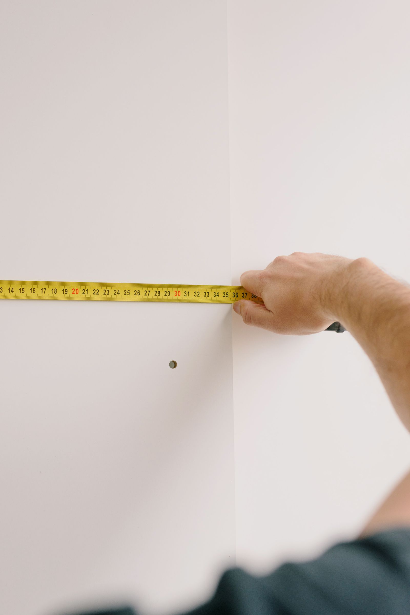 Main mesurant un mur intérieur après des travaux de rénovation