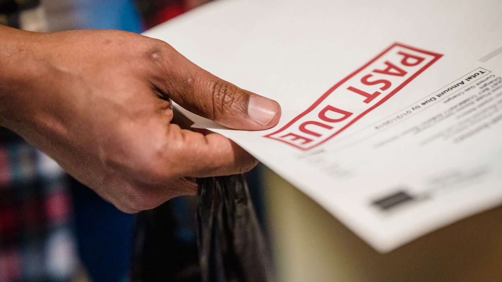 Main tenant un avis de paiement en retard au-dessus d’un bureau