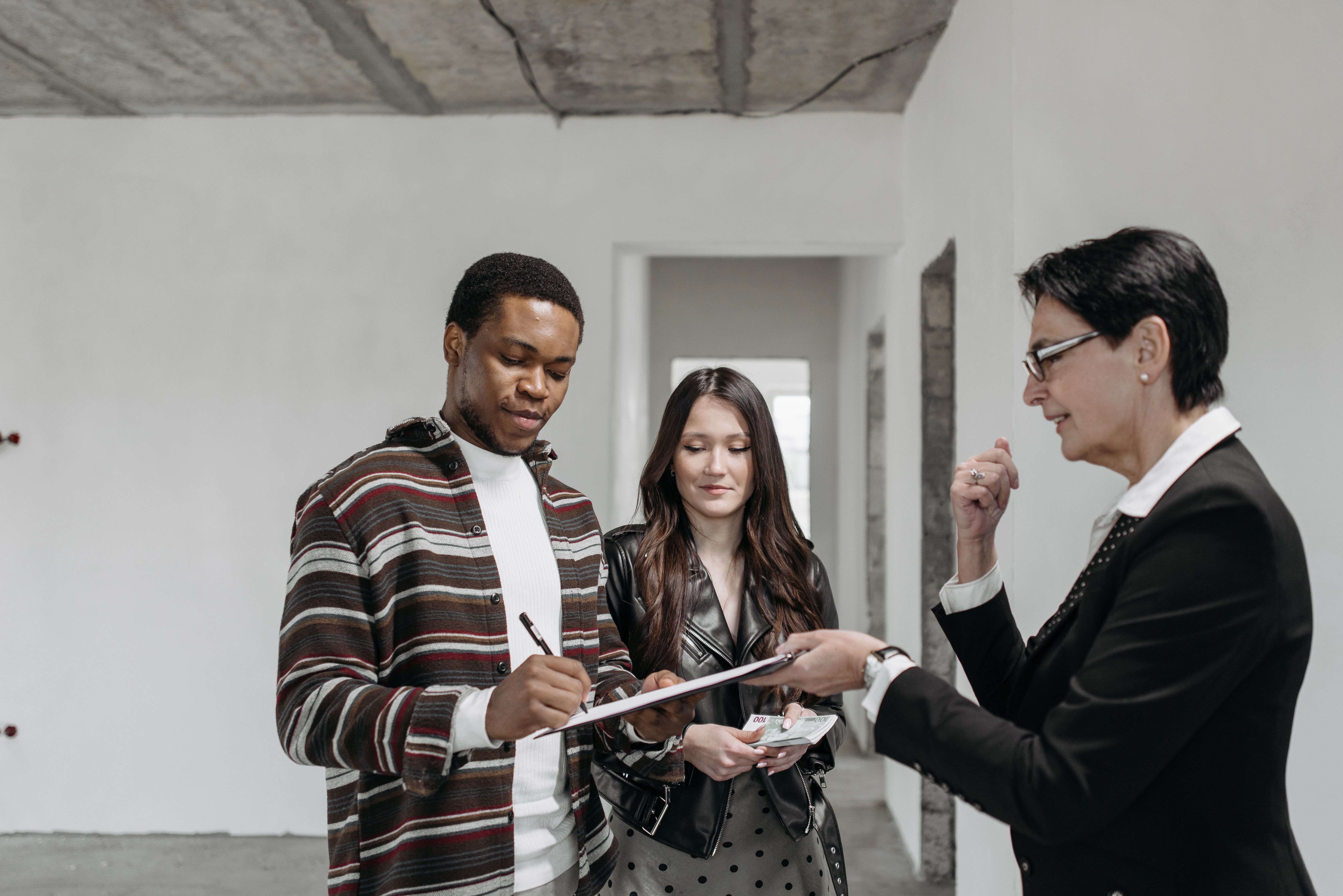 Couple examinant et signant des documents immobiliers avec une professionnelle