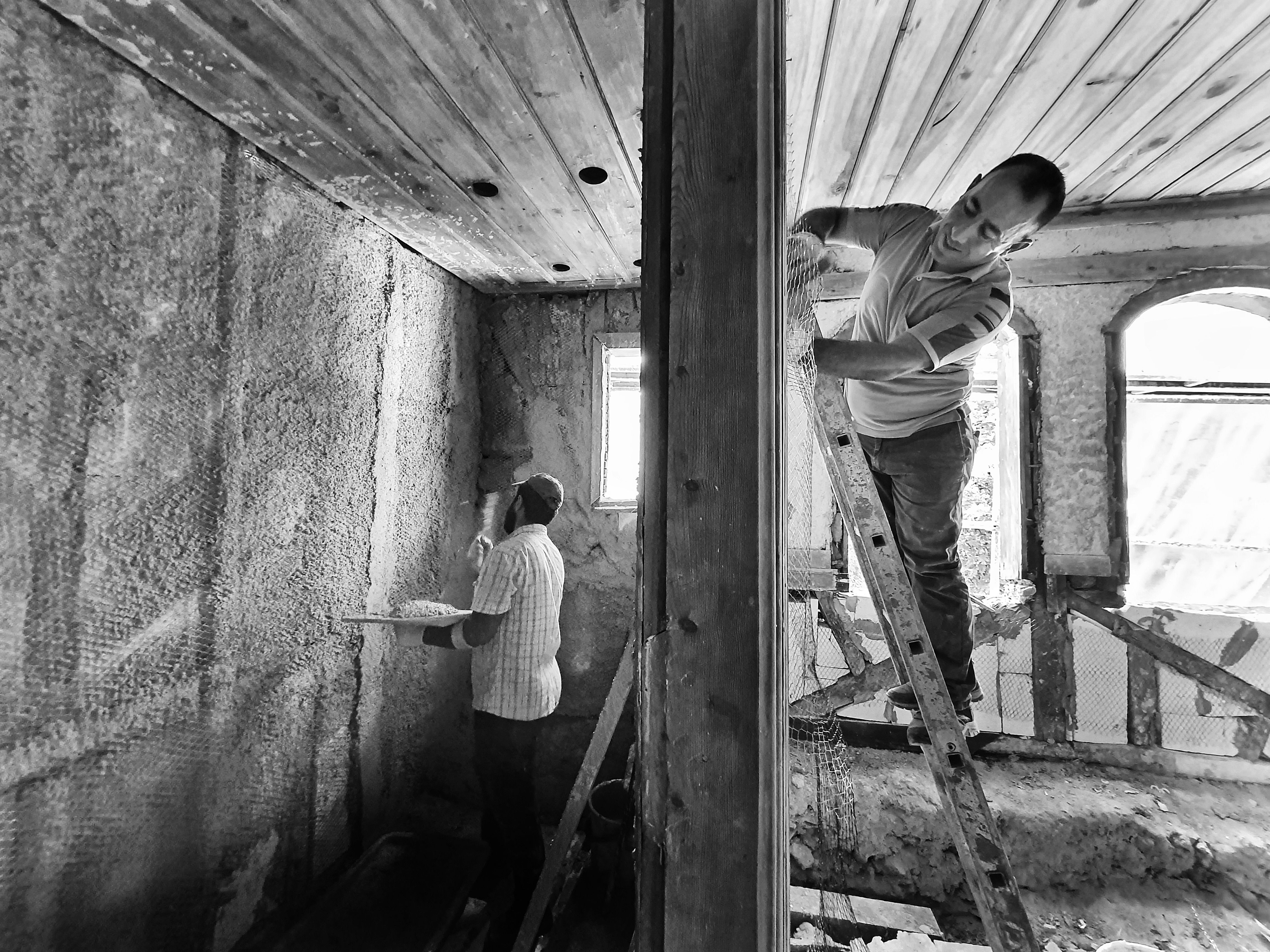 Artisans appliquant un enduit sur les murs d’une pièce en rénovation