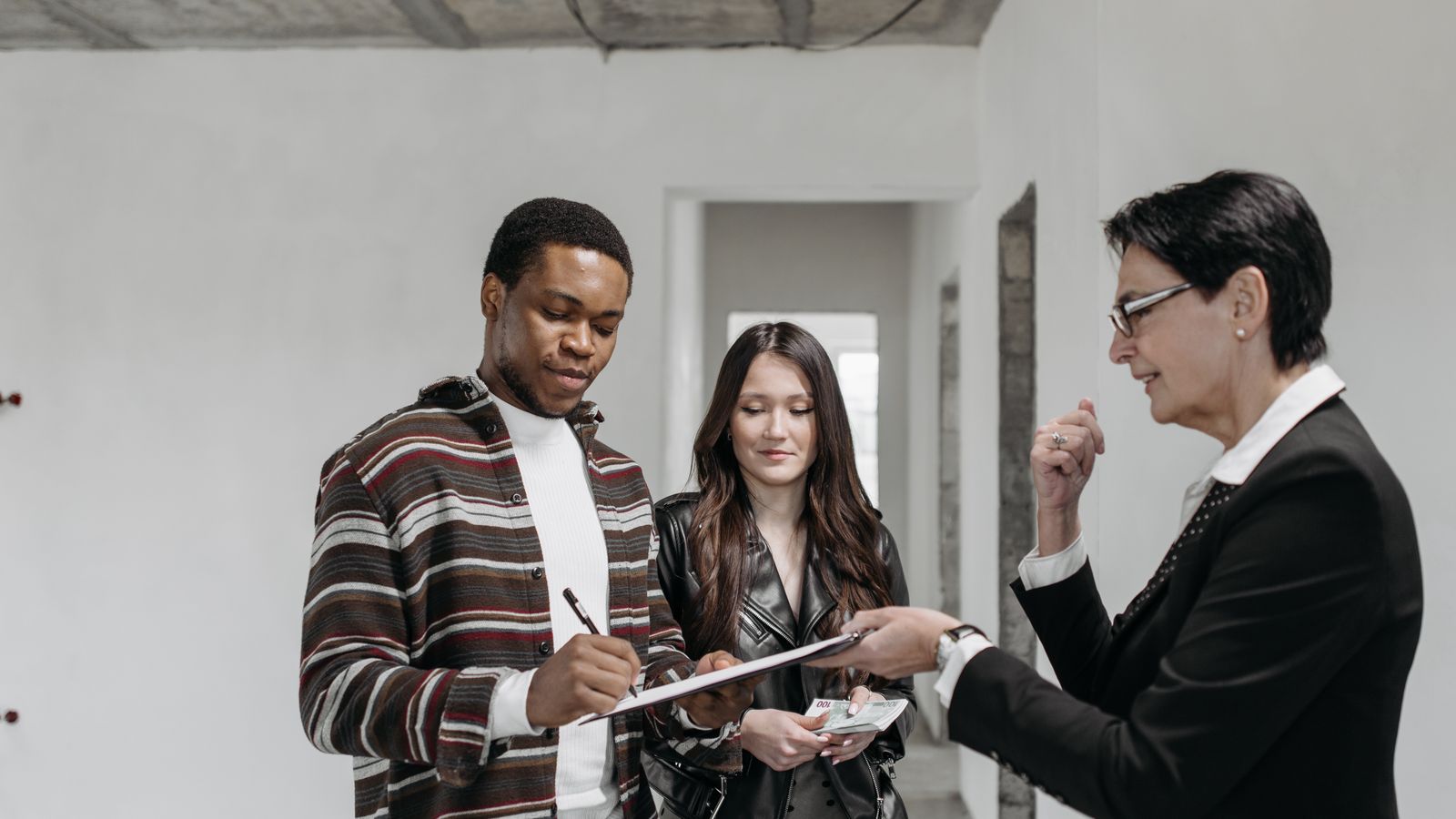 Acquéreurs signant des documents immobiliers avec une professionnelle