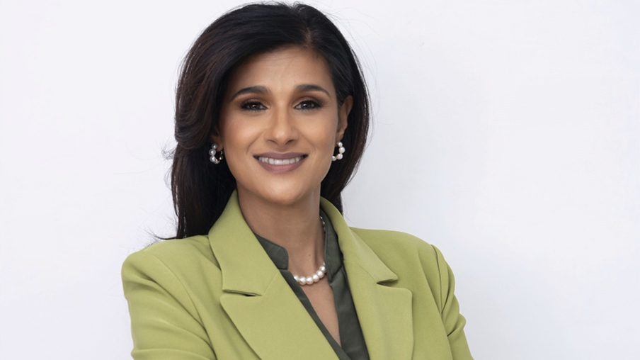 A woman wearing a green jacket and pearl earrings. - New Leaders Images