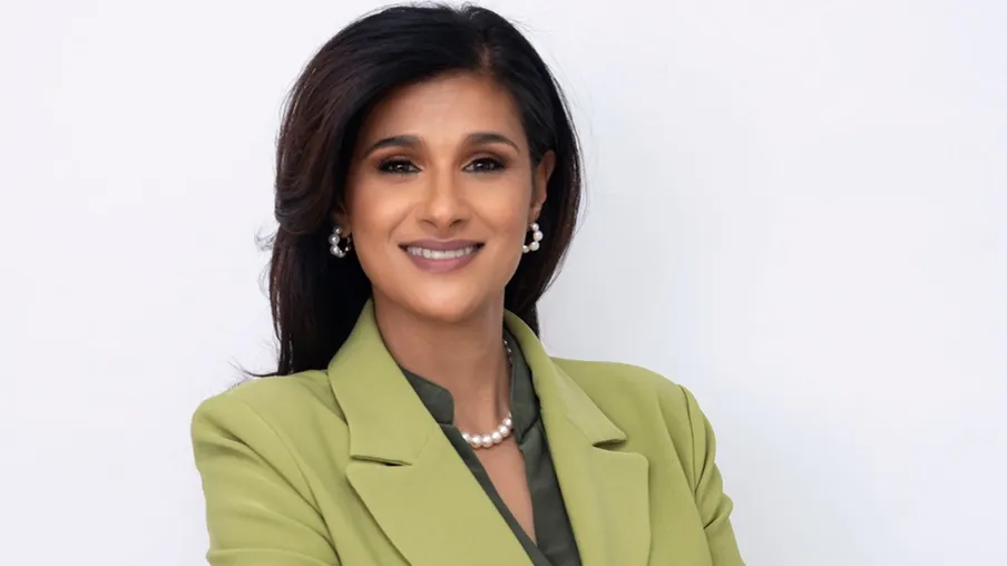 A woman wearing a green jacket and pearl earrings. - New Leaders Images