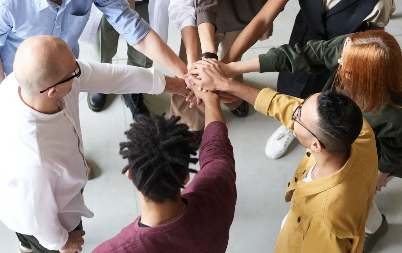 A group of people with glasses and different colored shirts are holding hands. - New Leaders Images