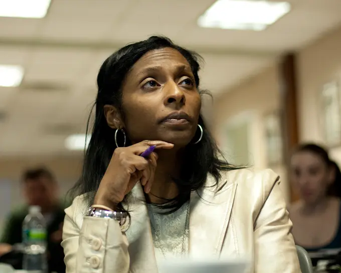 A woman in a cream jacket with round earings