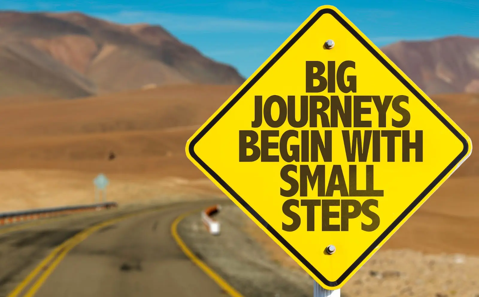 A sign next to the road: Big journeys begin with small steps