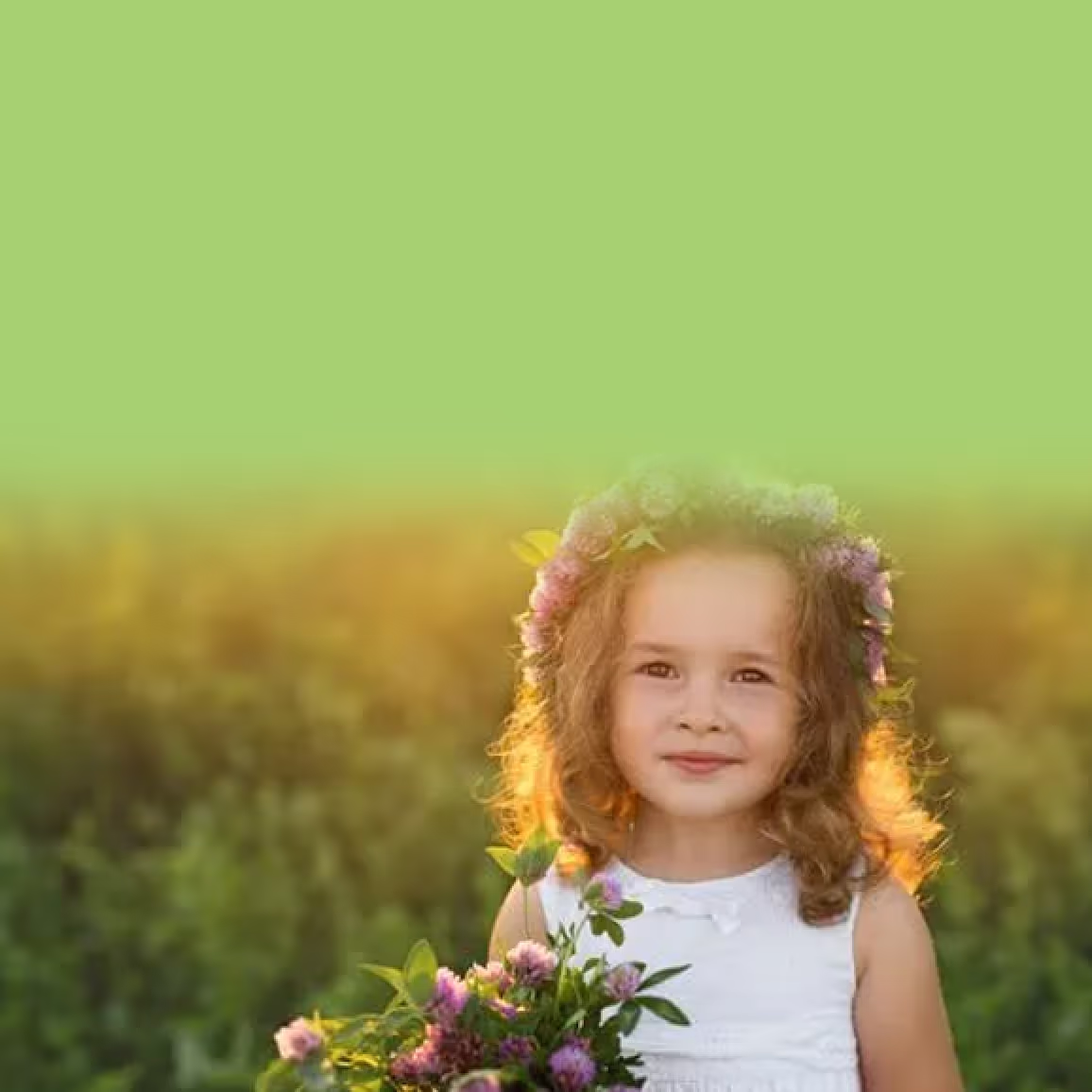 Little girl in a field outside wearing a flower headband and holding a bouquet.