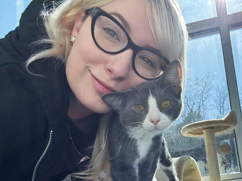 Woman in glasses hugging a gray kitten