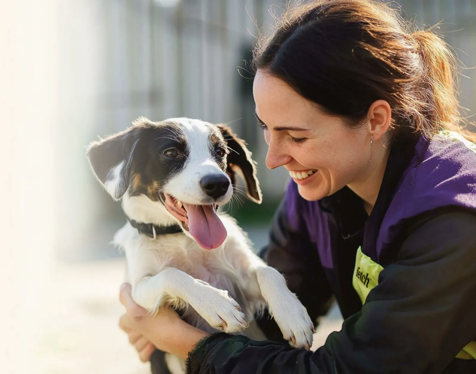 A Fetch team member holding a shelter dog and smiling.