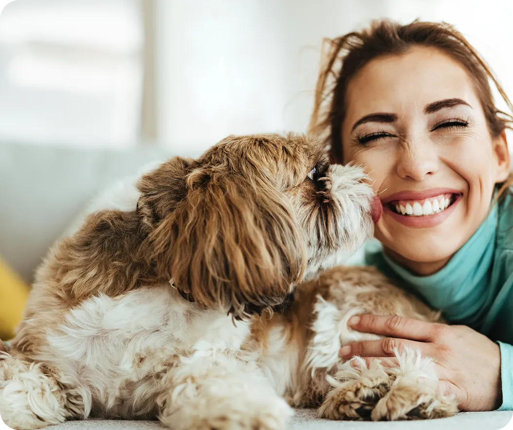 A happy woman getting kisses from their dog.