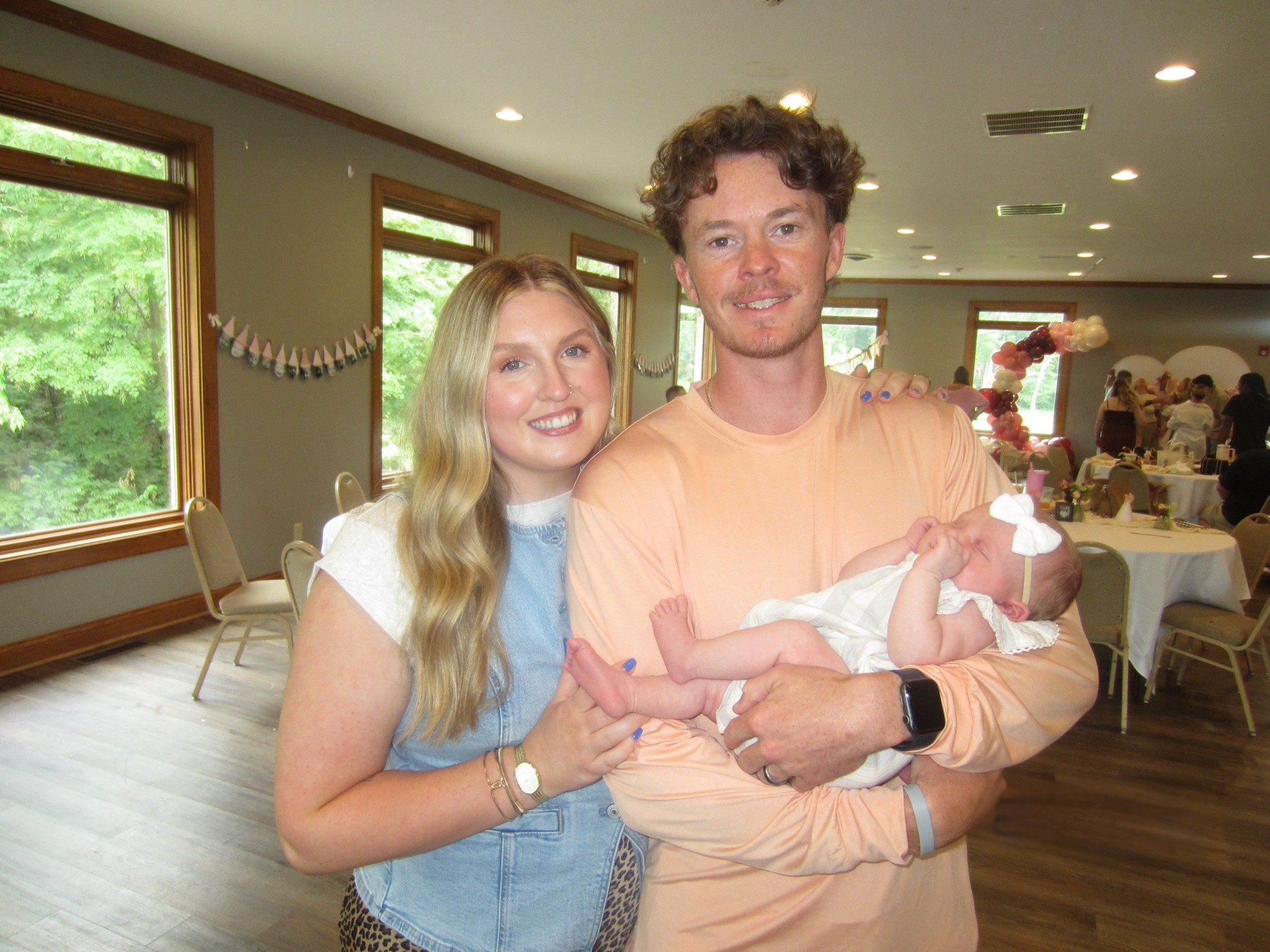 A woman hugging a man holding a baby.