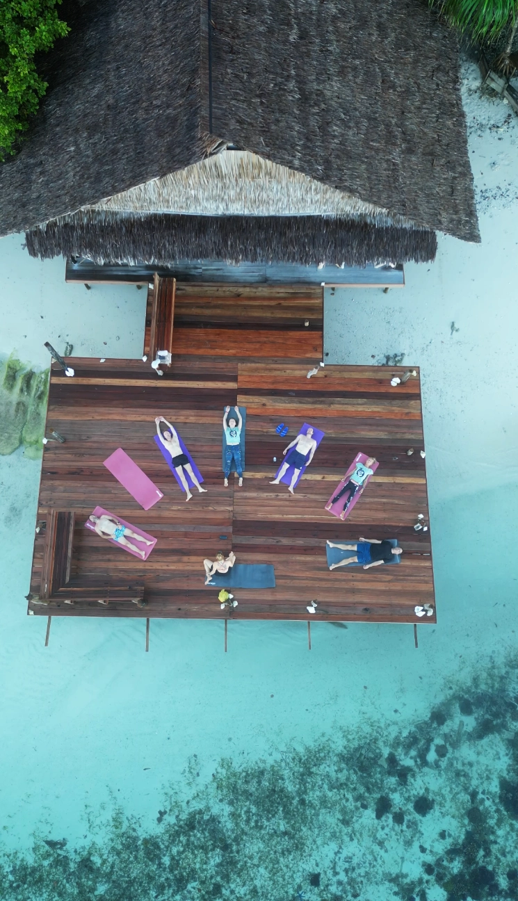 Freediving retreat in Raja Ampat guests ding morning yoga on the deck