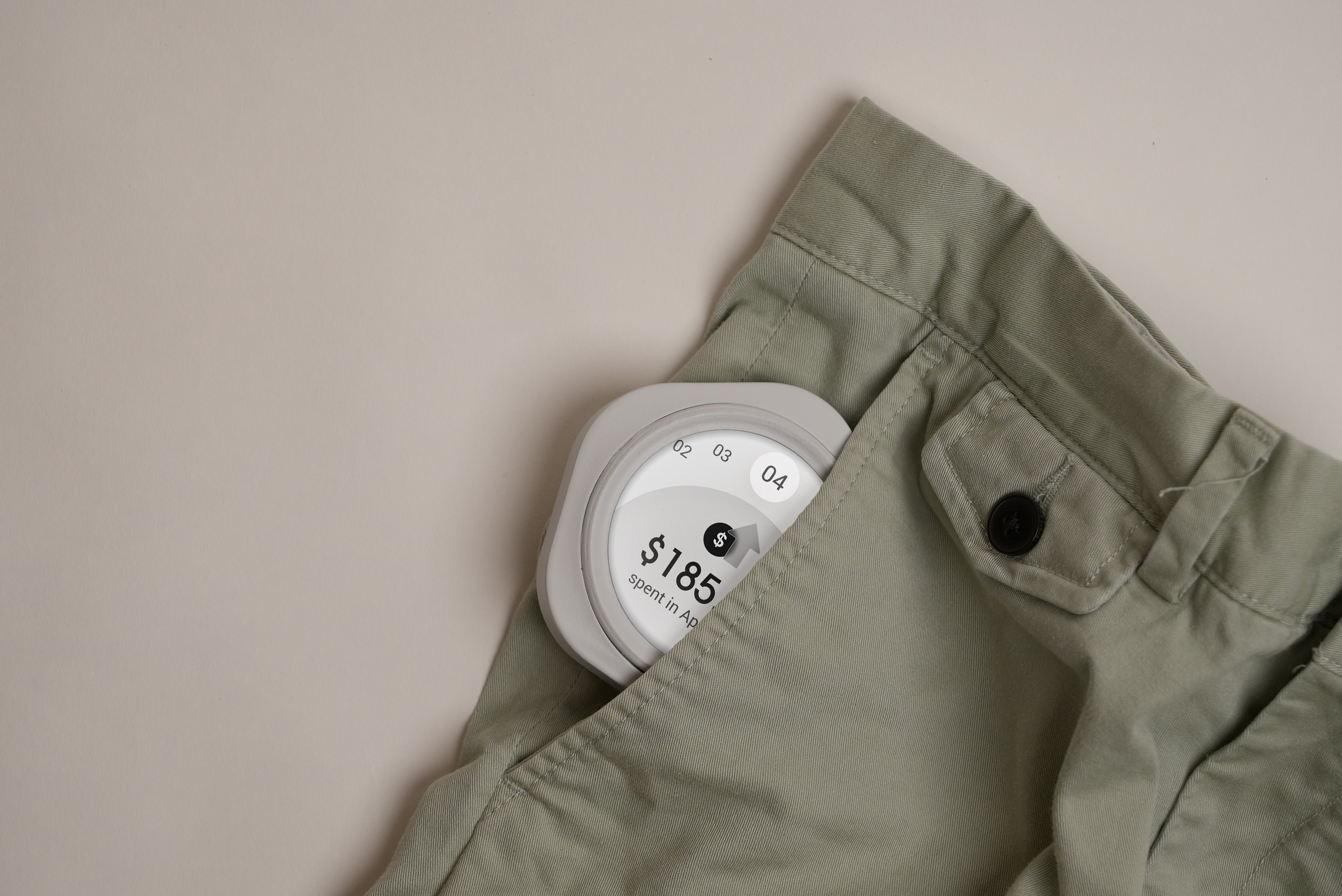Smartwatch with a financial app showing $185 spent in April, partially tucked into a green pants pocket.